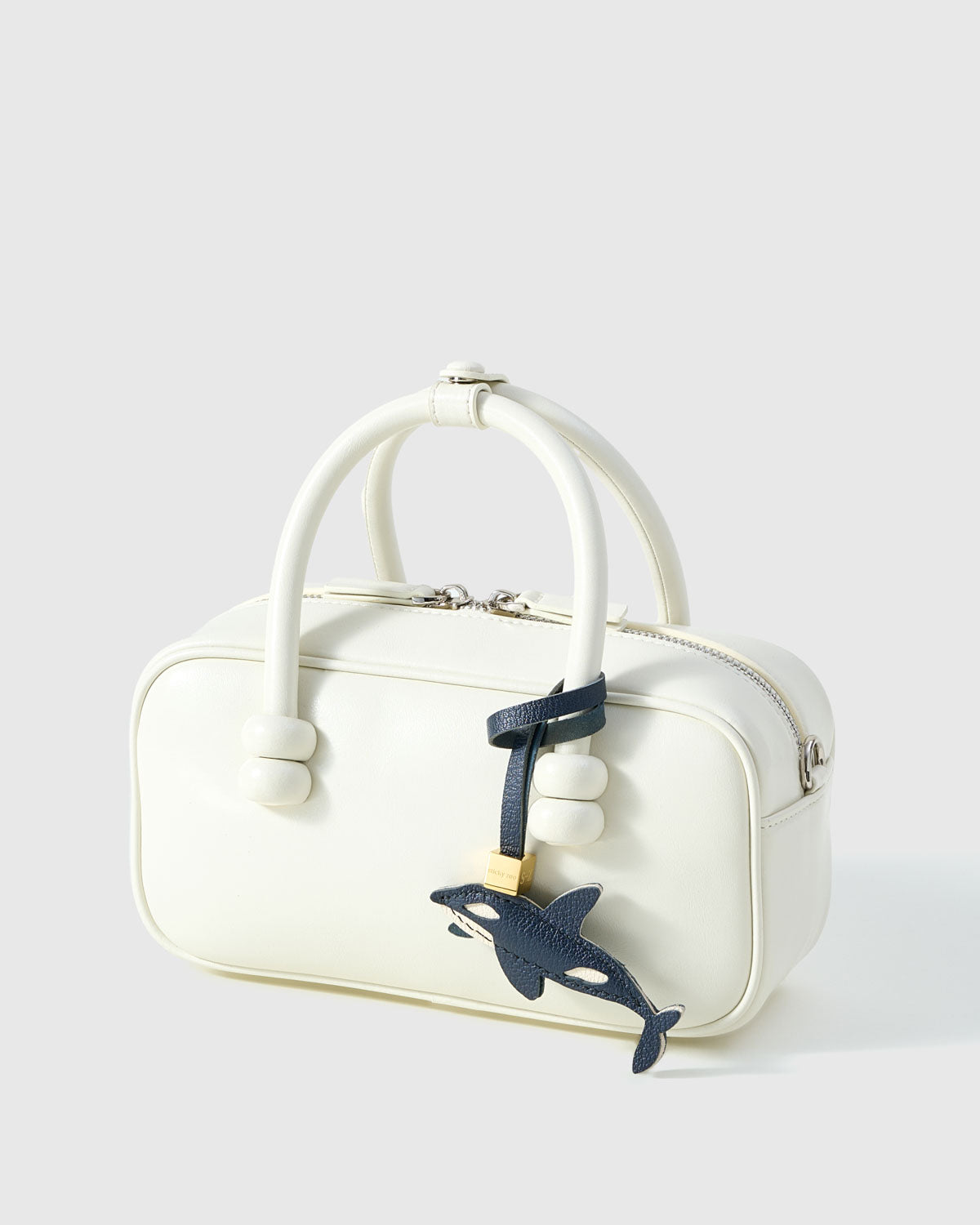 {{5,000+ Reviews.}} Orca charm on a bag, side angle — 5,000+ reviews across STICKYZOO. Real French leather, 3 days by hand.