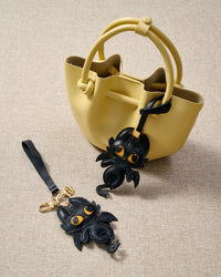 Black dragon charm styled on a bag — a small, specific piece that turns a simple bag into a personal one.