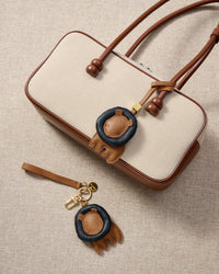 Close-up of the lion charm — hand-cut and hand-stitched panels of French Alran goatskin. Every layer by hand.