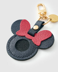 Close-up of the black Mickey AirTag holder — red bow, round ears, stitched edges. Every panel by hand.
