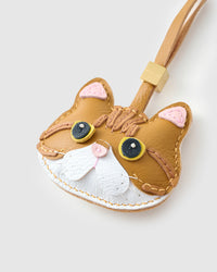 Tight close-up of the Persian face — yellow eyes in real leather, chestnut tabby forehead, pink inner ears. Every panel by hand.