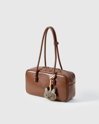 Tonkinese on a warm brown leather top-handle bag, side angle — real French leather, 3 days by hand.
