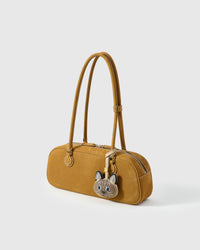 Tonkinese charm on a mustard-yellow suede top-handle bag, side angle — French Alran leather from Tarn, France, Entreprise du Patrimoine Vivant.