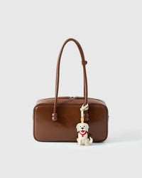 Handmade Golden Retriever leather bag charm clipped to a handbag — French Alran goatskin, 5-day artisan build. STICKYZOO.