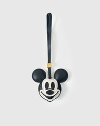 Mickey-style charm handmade from French Alran genuine goatskin — deep black head, round ears, white face mask, stitched eyes, cream-outlined smile, navy leather strap. Three days by hand. Arrives in luxury gift packaging. Designed in Amsterdam.