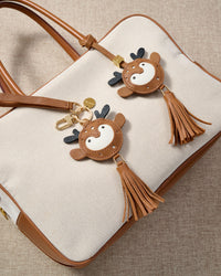 Close-up of the deer charm — hand-cut and hand-stitched panels of French Alran goatskin. Every layer by hand.