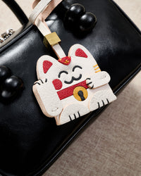 Maneki Neko (Lucky Cat) charm styled on a bag — a small, specific piece that turns a simple bag into a personal one.