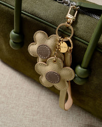 STICKYZOO Twin Flowers Charm — hand-cut, hand-stitched twin five-petal blooms on gold keychain in French Alran goatskin. Designed in Amsterdam.