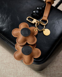 STICKYZOO Twin Flowers Charm — hand-cut, hand-stitched twin five-petal blooms on gold keychain in French Alran goatskin. Designed in Amsterdam.