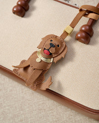 Handmade Golden Retriever leather bag charm clipped to a handbag — French Alran goatskin, 5-day artisan build. STICKYZOO.
