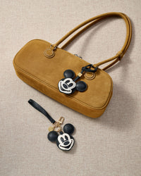 Close-up of the Mickey charm — black body, white face mask, cream-outlined smile, every layer stitched through real leather.