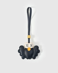 Black Hootie the Owl charm handmade from French Alran genuine goatskin — deep black body, spread wings, cream-ringed X-stitched eyes, orange beak, navy leather strap. Three days by hand. Arrives in luxury gift packaging. Designed in Amsterdam.