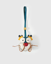 Colorful dragon charm handmade from French Alran genuine goatskin — white body, teal head, big round eyes, yellow horns, red leather heart on chest, long tan leather whiskers, teal leather strap. Three days by hand. Arrives in luxury gift packaging. Designed in Amsterdam.