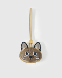 Tonkinese cat charm handmade from French Alran genuine goatskin — warm mushroom body, dark brown forehead stripes, pale blue eyes, dark ears with tan centres, cream leather strap. Three days by hand. Arrives in luxury gift packaging. Designed in Amsterdam.