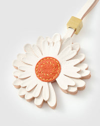 STICKYZOO Daisy Charm clipped to a handbag — handmade French Alran goatskin in white with orange suede centre. 3-day artisan build.