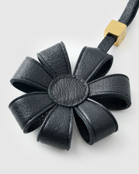 STICKYZOO Daisy Bag Charm clipped to a handbag — handmade French Alran goatskin in black. 3-day artisan build.