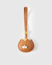 Bread Kitty charm handmade from French Alran genuine goatskin — golden-brown bread-bun shape with a small ginger cat face, pink heart nose, fine whiskers, tan leather strap. Three days by hand. Arrives in luxury gift packaging. Designed in Amsterdam.