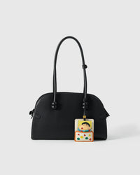 Shinchan nap charm styled on a bag, front — a small, specific piece that turns a simple bag into a personal one.