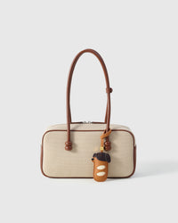 Handmade Dachshund Sausage Pup leather bag charm shown clipped to a canvas handbag — caramel-tan French Alran goatskin body with cream paw cutouts. STICKYZOO Amsterdam design.