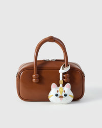 Light Silver Tabby charm styled on a warm brown leather box bag, front — a small, specific piece that turns a simple bag into a personal one.