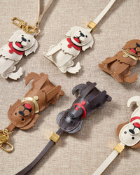 Close-up of handmade Golden Retriever leather bag charm — hand-stitched visible edges on French Alran goatskin, 18K gold-plated cube hardware. STICKYZOO.