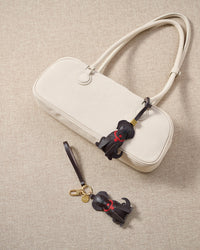 Close-up of handmade Golden Retriever leather bag charm — hand-stitched visible edges on French Alran goatskin, 18K gold-plated cube hardware. STICKYZOO.