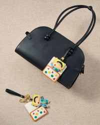 Both editions of the Shinchan nap charm — leather strap for bags, or 18K gold-plated keychain clip.