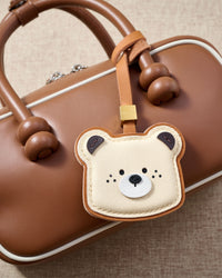 Toast Bear charm close on a warm tan leather top-handle bag — a small, warm piece that makes people smile before they even ask where it's from.