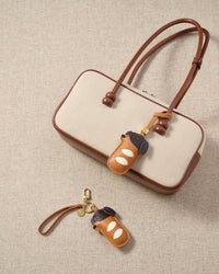 Close-up of handmade Dachshund Sausage Pup leather bag charm shown on a handbag — full-grain French Alran goatskin, 18K gold-plated hardware. STICKYZOO.