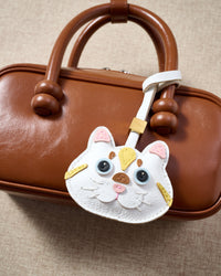 Light Silver Tabby charm hanging on a warm brown leather box bag, close detail — rated 4.9★ by thousands of buyers. Real French Alran leather, 3 days by hand.