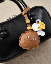 Chicken wing charm styled on a bag, front — a small, specific piece that turns a simple bag into a personal one.
