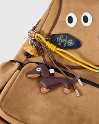 STICKYZOO Woofy Dogface Backpack charm bundle close-up showing handmade leather dachshund, croissant charm, and Hotel California tag