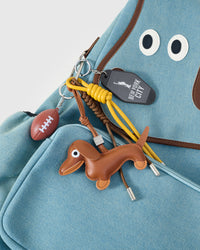 STICKYZOO Capster Backpack charm bundle close-up showing black leather dachshund, yellow skateboard charm, and mini game keychain
