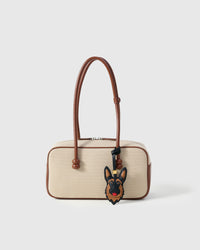Handmade German Shepherd leather bag charm shown on a cream canvas handbag — hand-layered black and tan French Alran goatskin panels. STICKYZOO collectible.