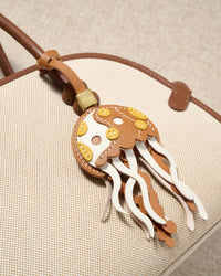 Jellyfish charm styled on a bag, front — a small, specific piece that turns a simple bag into a personal one.