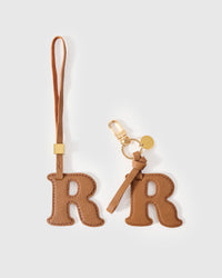 Every edge of the R is cut by hand from French Alran goatskin and stitched through real leather. Three days per piece. Small-batch, made to be kept.