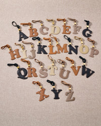 Every panel of the alphabet charm is cut by hand and stitched through real French leather. Layered slowly for depth — no prints, no stamps.