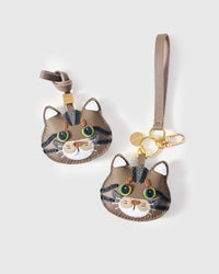 Both editions of the tabby cat side by side — leather strap loop for bags, or 18K gold-plated keychain clip.