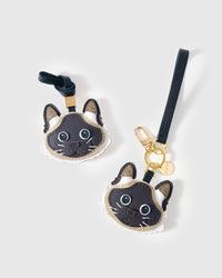 Both editions of the Siamese side by side — leather strap loop for bags, or 18K gold-plated keychain clip.