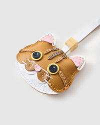 Tight close-up of the orange tabby face — gold eyes in real leather, tabby stripes hand-stitched, pink nose, white chin. Every panel by hand.
