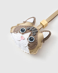 Tight close-up of the Latte Paws Ragdoll face, angled — vivid blue eyes in real leather, deep brown markings, pink nose, white face mask. Every panel by hand.