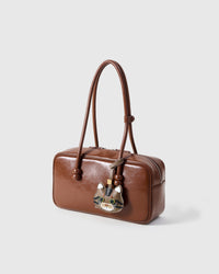 Tabby cat charm on a warm brown leather top-handle bag, side angle — rated 4.9★ by thousands of buyers. Real French Alran leather, 3 days by hand.