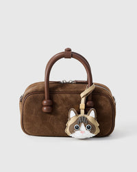 Latte Paws Ragdoll styled on a brown suede box bag, front — a small, specific piece that turns a simple bag into a personal one.