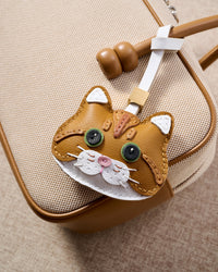 Close-up of the ginger British Shorthair on a cream canvas bag — real leather that softens over time, carried every day.