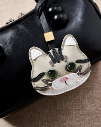 Silver Tabby American Shorthair hanging on a black top-handle bag, angled detail — rated 4.9★ by thousands of buyers. Real French Alran leather, 3 days by hand.
