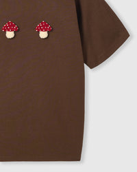Side detail of Mushroom T-Shirt in brown showing hem and plush mushrooms
