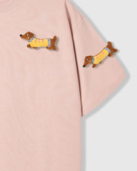 Detail of plush dachshunds on body and sleeve of STICKYZOO pink Dachshund Parade T-Shirt