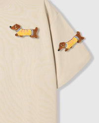 Detail of plush dachshunds on body and sleeve of STICKYZOO cream Dachshund Parade T-Shirt