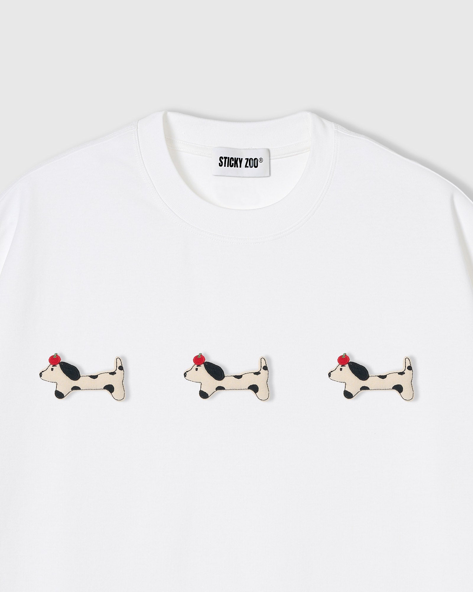 {{Not printed — hand-stitched}} Three plush spotted dachshund appliqués with red beret detail on STICKYZOO white oversized t-shirt