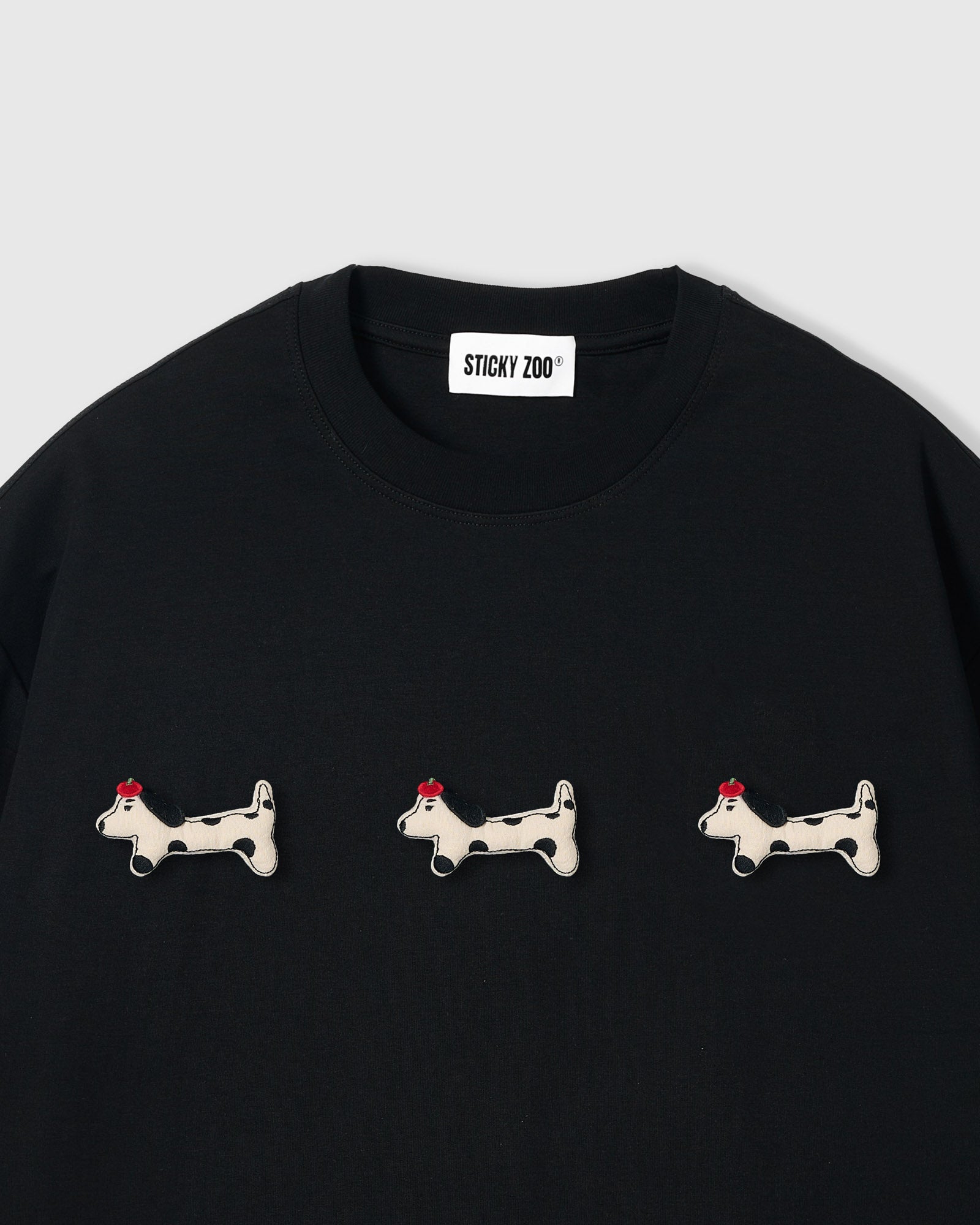 {{Not printed — hand-stitched}} Three plush spotted dachshund appliqués with red beret detail on STICKYZOO black oversized t-shirt